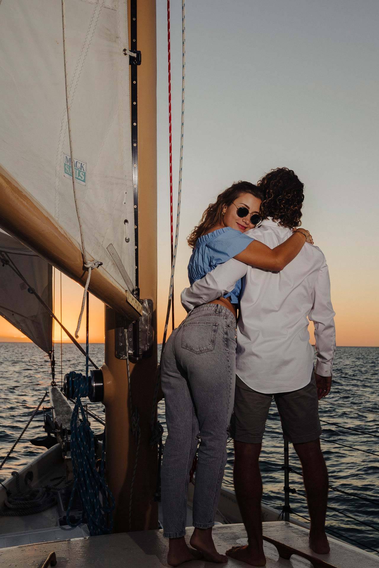 A couple on a sailboat looks over the water during a sunset cruise in Key West