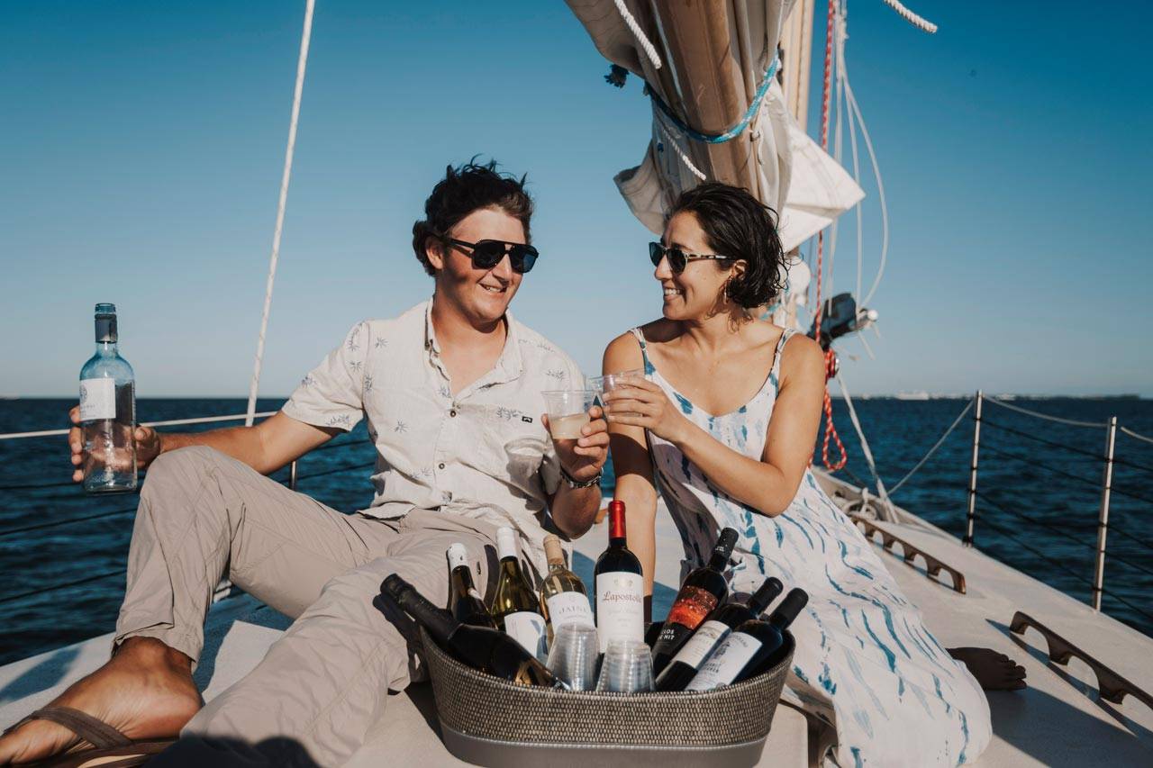 A young couple enjoy a glass of white wine while on a sailing charter with Danger Charters in Key West, FL