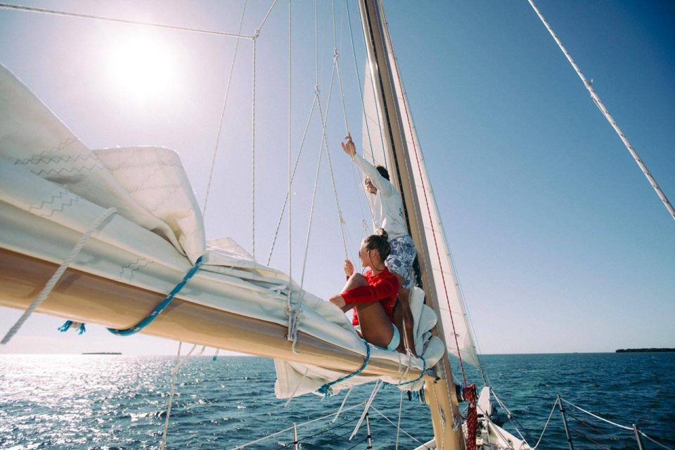 Two crew members lounge on the mast of a schooner in Key West