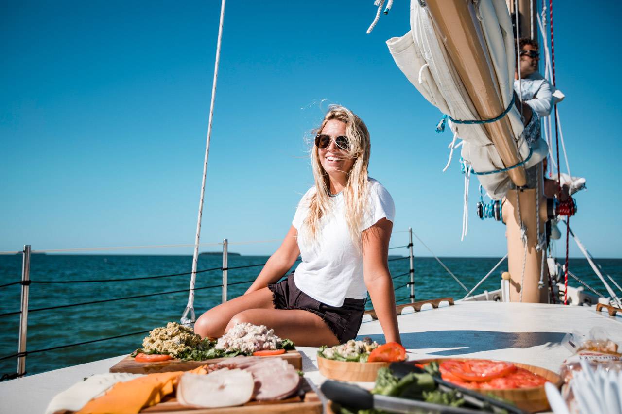 A blond woman smiles while relaxing aboard a schooner in Key West