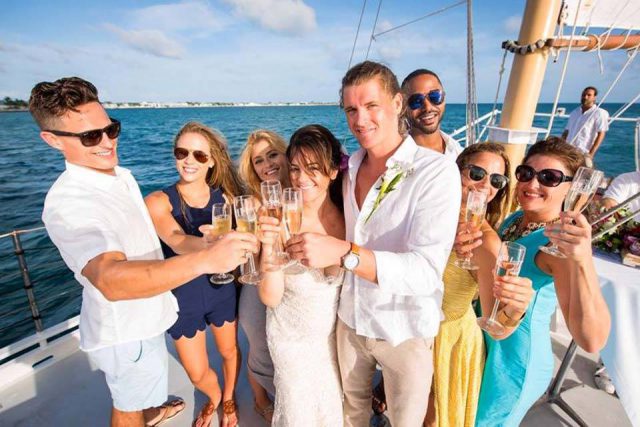 A young couple drinks champagne and enjoys a sailboat wedding with friends in Key West