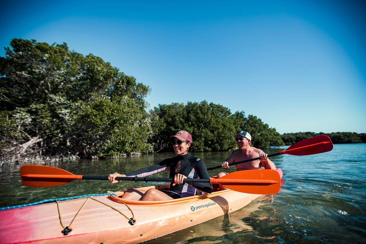 A couple in an orange kayak paddle through the mangroves in Key West, FL