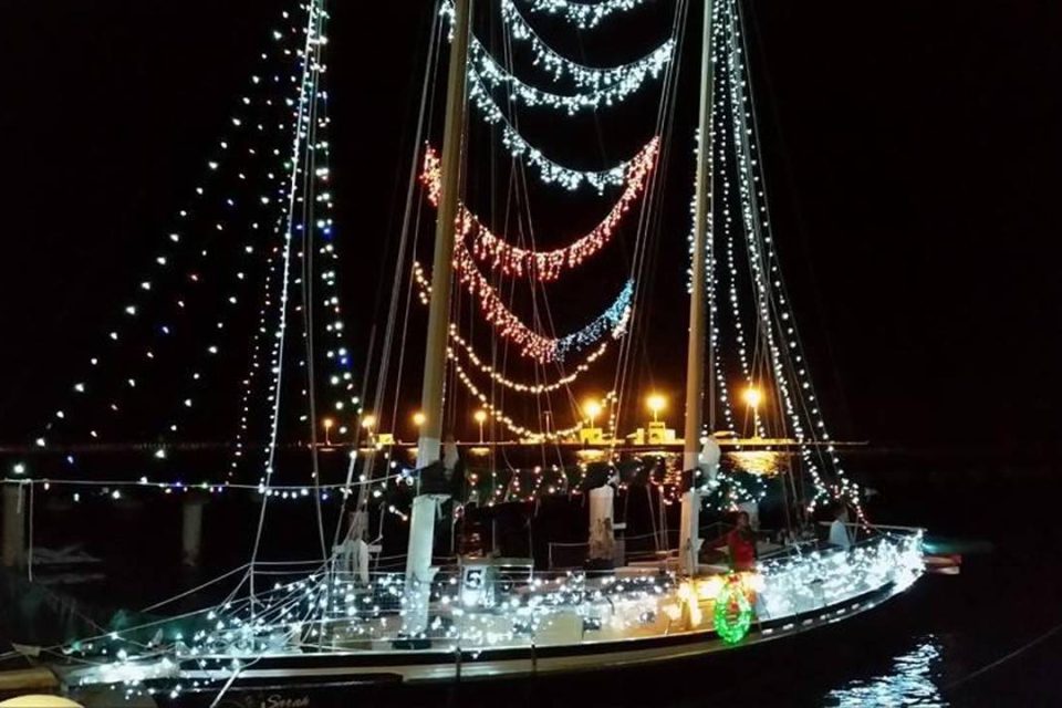 A boat illuminated by Christmas lights at night during the Key West holiday boat parade
