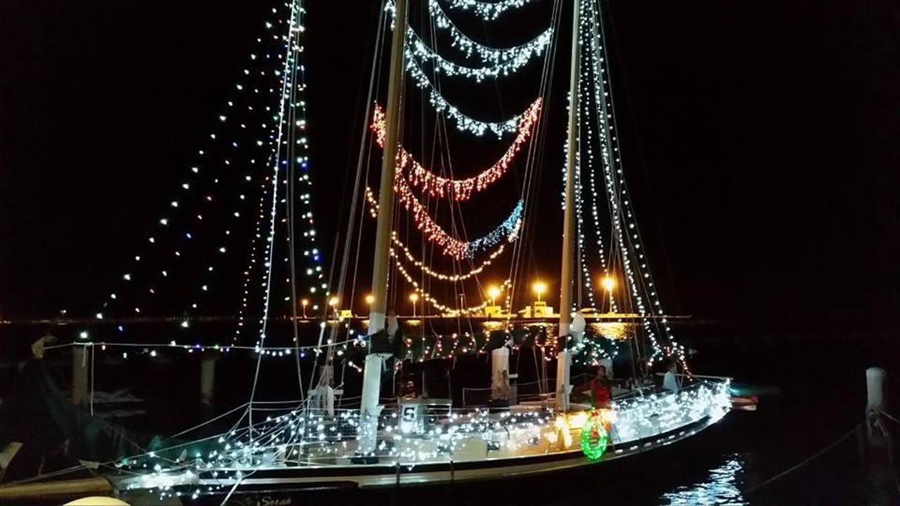 A boat illuminated by Christmas lights at night during the Key West holiday boat parade