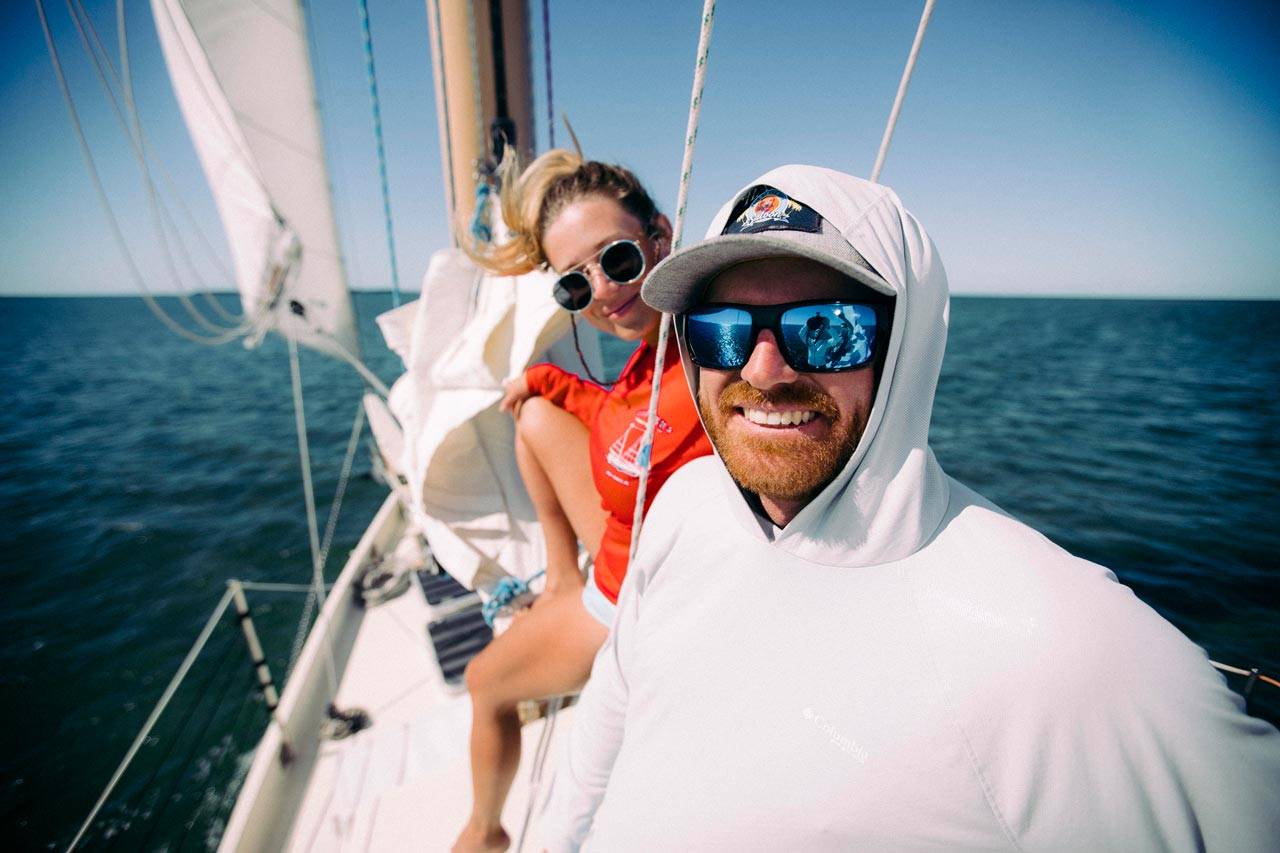 Young woman and man smiling and laughing in the sun while sailing on a schooner in Key West