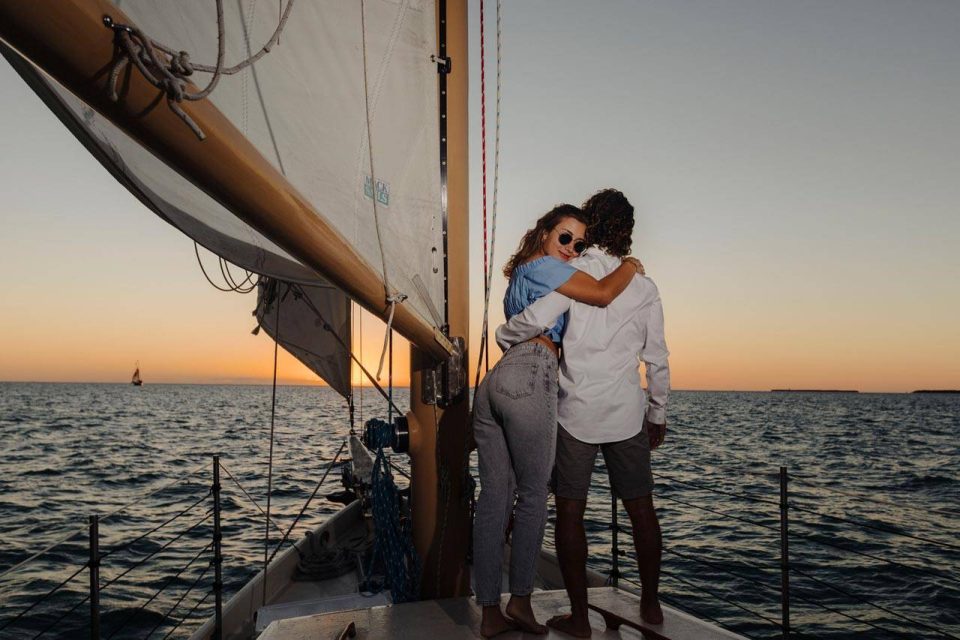 A couple on a sailboat looks over the water during a sunset cruise in Key West