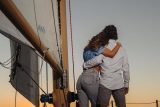 A couple on a sailboat looks over the water during a sunset cruise in Key West