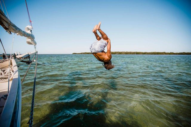 Man in board shorts does a summersault off a schooner in Key West