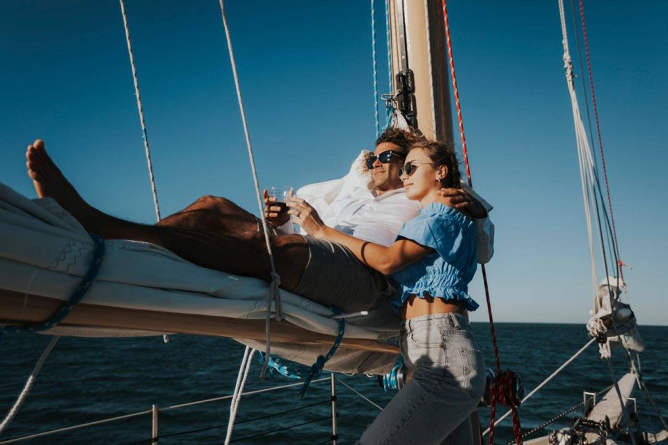 A young couple drinks a glass of wine and relaxes onboard a schooner in Key West